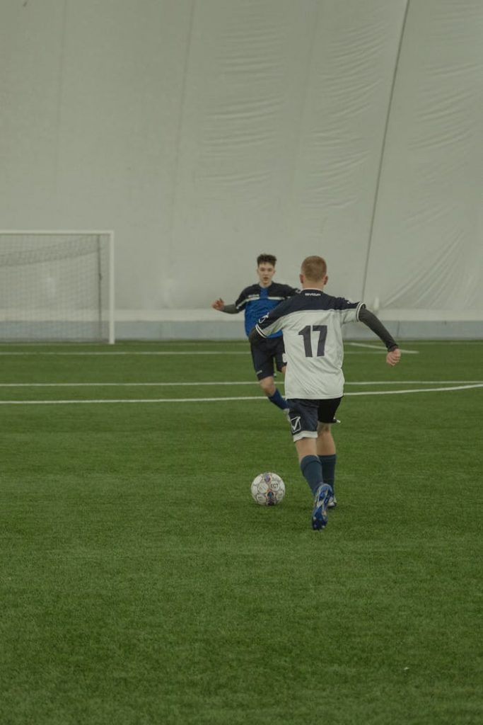 Two soccer players engaging in a competitive indoor match on a green field.